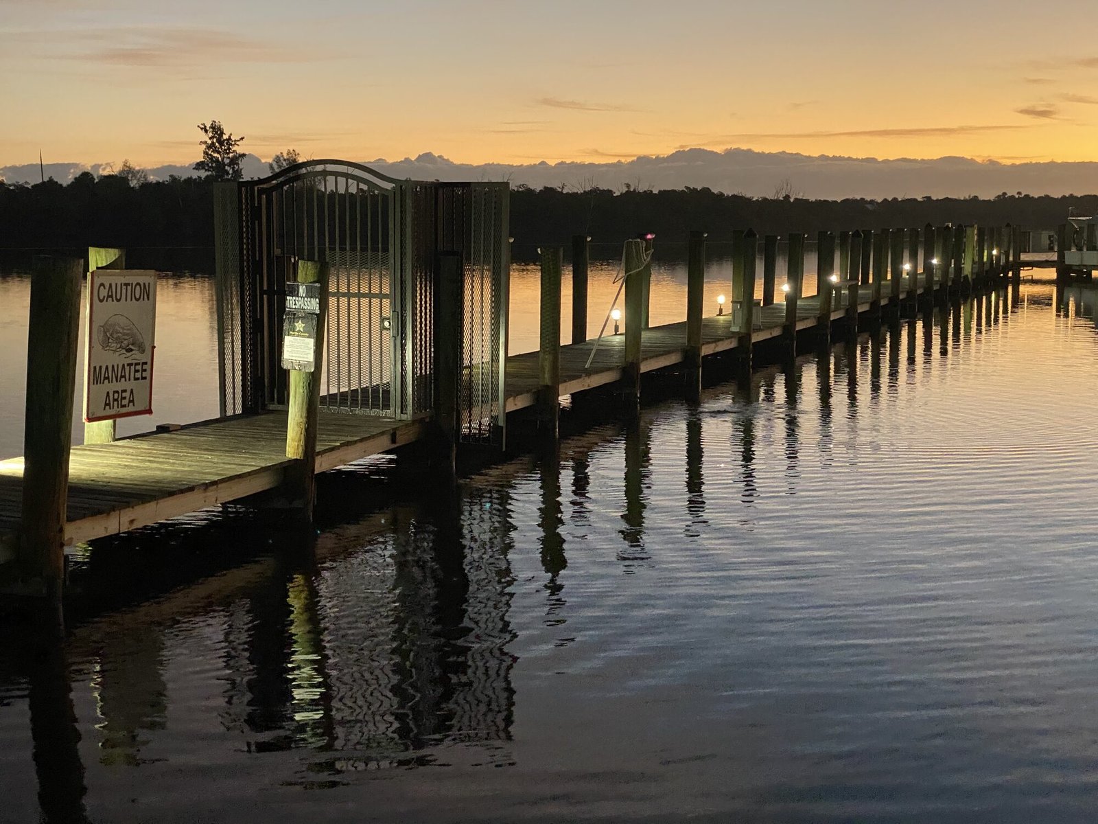 Community dock at sunset with manatee area signage