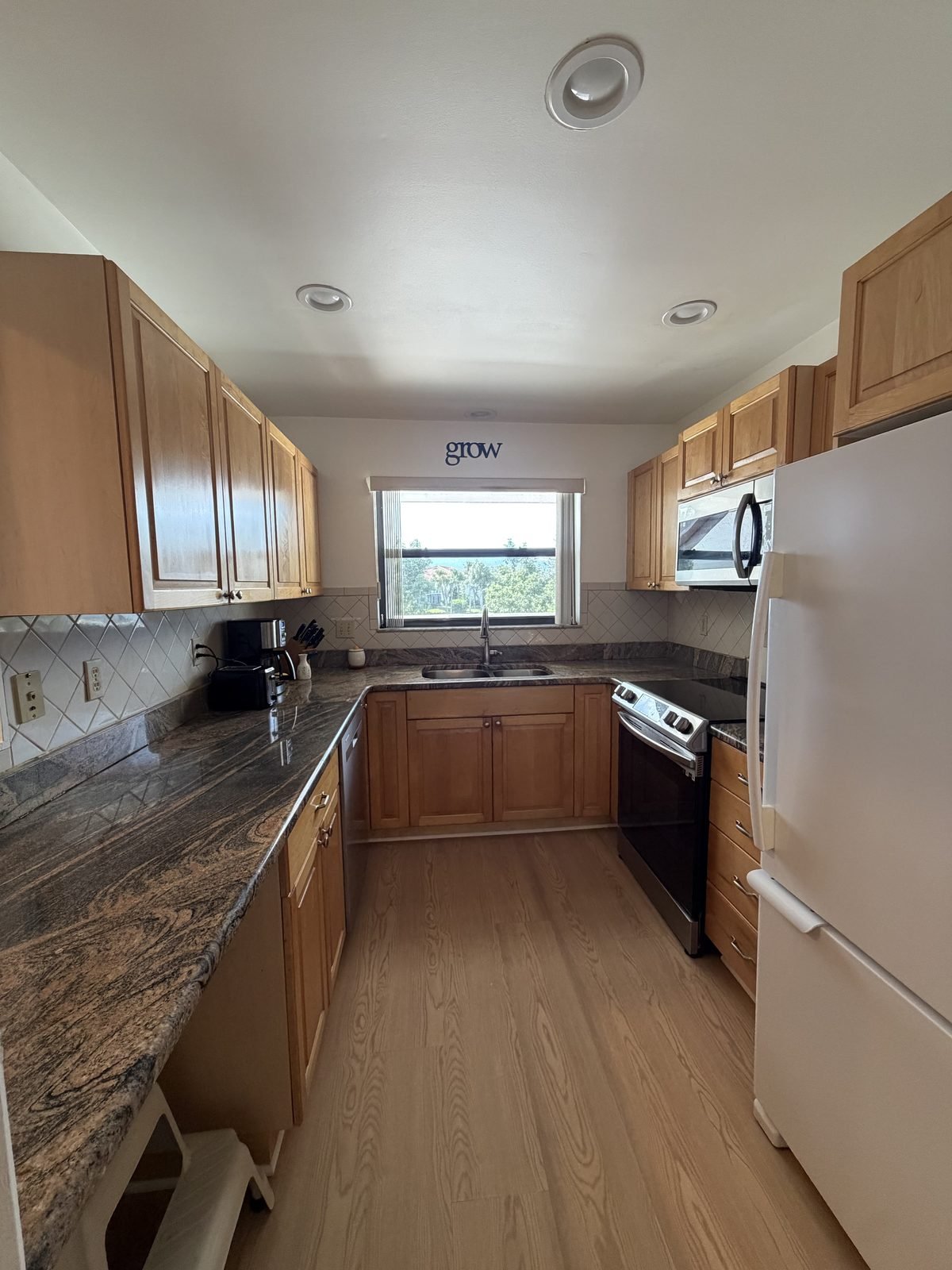 Kitchen with granite counters, wood cabinets, stainless appliances, and a window over the sink