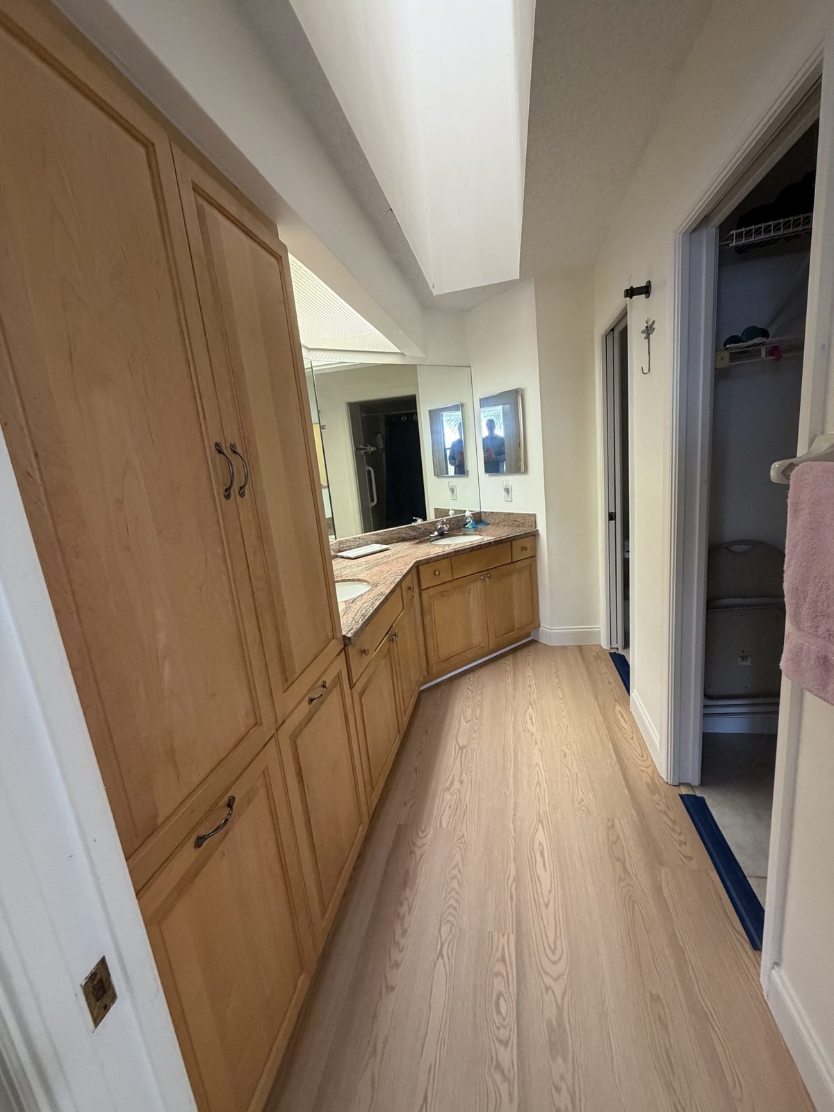 Master bathroom with dual-sink granite vanity, large mirror, linen storage, and walk-in closet