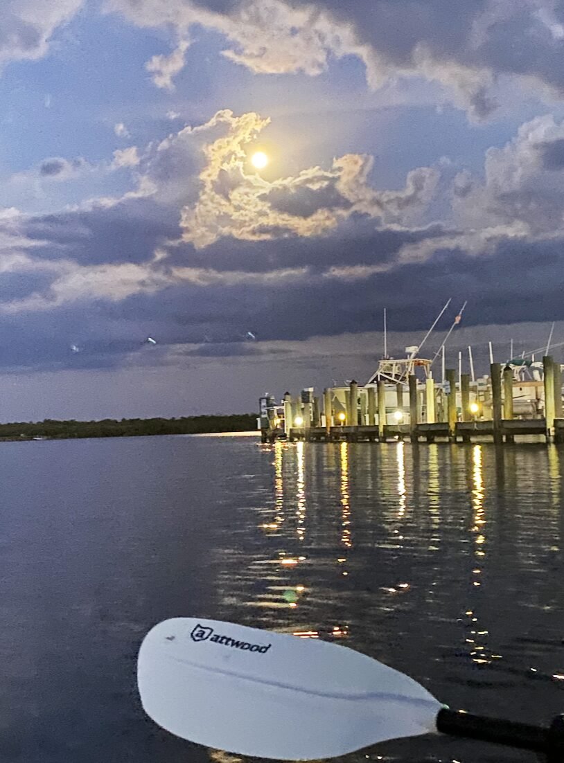 Moon over the water with a kayak paddle in the foreground